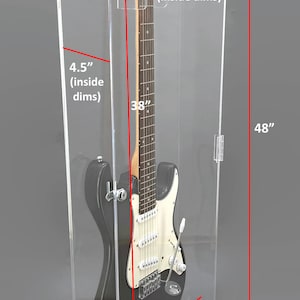 May include: Clear acrylic guitar display case with a black base. The case is 48 inches tall, 16.25 inches wide, and 7 inches deep. Inside dimensions are 4.5 inches deep and 15.25 inches wide. A black electric guitar is inside the case.