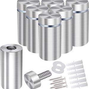 May include: A set of silver-colored standoffs for mounting signs or displays. The image shows multiple cylindrical standoffs with a brushed metal finish, along with screws, washers, and wall anchors. The standoffs have a modern, minimalist design.