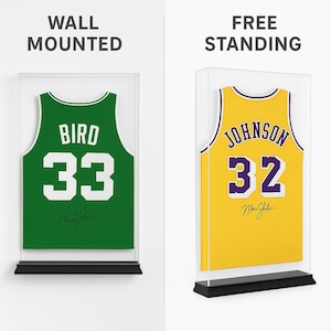 Puede incluir: Dos camisetas de baloncesto enmarcadas, una verde con "BIRD 33" y otra amarilla con "JOHNSON 32". Ambas camisetas se exhiben en vitrinas transparentes con bases negras, etiquetadas como "WALL MOUNTED" y "FREE STANDING".