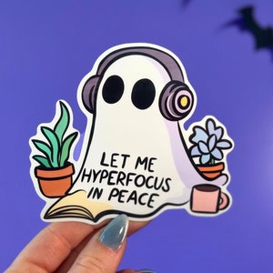 May include: A white ghost wearing headphones with the text "Let me hyperfocus in peace" and a plant in a pot on each side of the ghost.