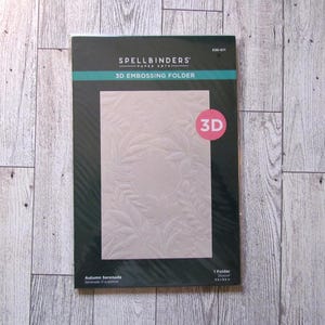 May include: A Spellbinders 3D embossing folder in a black package. The folder features a raised leaf design and the text "Autumn Serenade". The package is 5.5 x 8.5 inches.