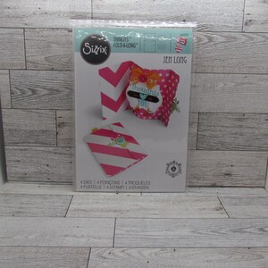 May include: A Sizzix Thinlits Fold-a-Long die set. The packaging features a pink and white chevron pattern, a pink and white striped pattern, and a pink polka dot pattern. The die-cut projects include a gift bag with the text "Thoughts of You".
