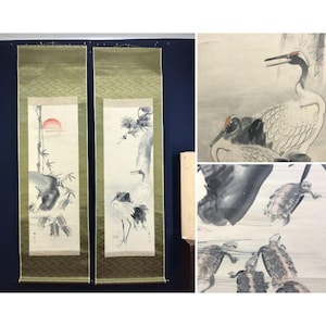 Op de afbeelding: Twee verticale Japanse schilderijen op rol met gouden zijden randen. De linkerrol toont bamboe en een rode zon. De rechterrol toont kraanvogels en een boom. Extra afbeeldingen tonen kraanvogels en schildpadden.