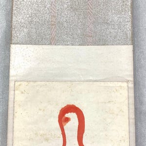 May include: An abstract artwork featuring a red, curved shape on a cream-colored background. The top portion has a textured, gray surface with vertical pink stripes. The artwork is framed with a light-colored border.