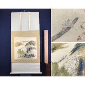 May include: An antique Japanese scroll painting depicting a landscape with a waterfall and a boat with a person. The scroll is mounted on a light blue backing with a wooden storage box. The artwork is in muted tones of green, blue, and beige.