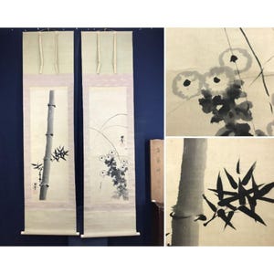 Op de afbeelding: Twee verticale Aziatische rolschilderijen met inkttekeningen van bamboe en bloemen. De rollen zijn crèmekleurig met lichtgroene en roze accenten. De bamboeschildering staat links en de bloemenschildering rechts.