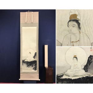 May include: A Japanese scroll painting featuring a seated figure with a halo. The artwork is primarily in black and white, with subtle color accents. The scroll is displayed against a dark blue background.