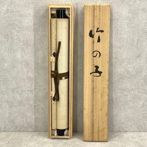 May include: A vintage Japanese scroll painting in a wooden box. The scroll is rolled up and secured with a brown cord. The box is made of light-colored wood, with Japanese characters printed on the side.