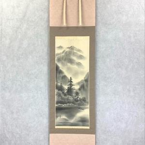 Peut inclure: Peinture japonaise sur rouleau représentant un paysage de montagne serein en nuances de gris et de blanc. L'œuvre présente un lac, des arbres et des montagnes, avec une bordure aux tons neutres et du matériel de suspension.