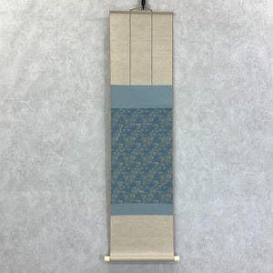 以下が含まれることがあります： 花柄の縦長の巻物。明るい青とベージュの配色です。中央のパネルは、明るい色合いの花柄の青い背景です。上部と下部のセクションはベージュです。