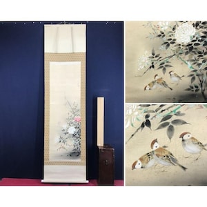 May include: An antique Japanese scroll painting featuring a floral arrangement with pink and white flowers. The scroll is framed with a beige border and has a cream-colored background. Additional images show detailed paintings of birds and flowers.