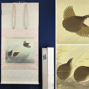 May include: A Japanese hanging scroll featuring a painting of three brown quail birds in a grassy field. One bird is in flight while two others stand on the ground. The scroll has a cream-colored border with gold accents and includes a storage box.