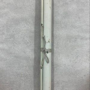 May include: A rolled-up scroll with a white paper surface, secured with a patterned ribbon and cord. The scroll has black caps on both ends. The paper shows signs of age, with some discoloration.