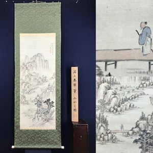 以下が含まれることがあります： グレーと黒の色合いで山岳風景を描いた伝統的なアジアの巻物絵画。このアートワークは、山、木、人物のいる小さな橋の詳細なシーンを特徴としています。巻物は、緑色の模様のボーダーで縁取られています。