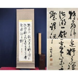 Op de afbeelding: Een vintage Japanse rol met kalligrafie in zwarte inkt op crèmekleurig papier. De rol wordt gepresenteerd met een houten deuvel en een donkerbruine doos. Close-up beelden van de kalligrafie zijn ook inbegrepen.