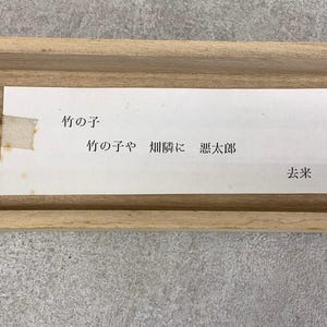 May include: A rectangular wooden frame with a white paper insert. The paper has Japanese text in black ink. The text includes the words "竹の子" and other Japanese characters. The paper is slightly yellowed with age.