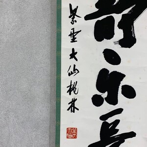 Puede incluir: Un pergamino vertical con caligraf&iacute;a japonesa en tinta negra sobre papel blanco. La caligraf&iacute;a incluye texto vertical a la izquierda y caracteres grandes y en negrita a la derecha. Un sello rojo es visible en la parte inferior. El pergamino tiene un borde verde a la izquierda.