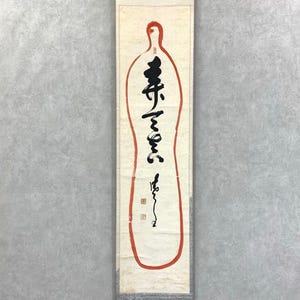 May include: A vertical scroll with a red outline in the shape of a bottle. The scroll features black calligraphy and two red square seals. The background is a light cream color.