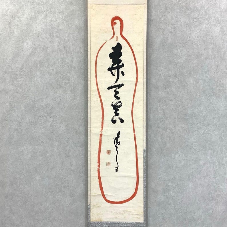 May include: A vertical scroll with a red outline in the shape of a bottle. The scroll features black calligraphy and two red square seals. The background is a light cream color.