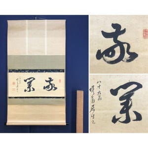 May include: A vertical hanging scroll featuring black ink calligraphy on a beige paper background. The scroll includes a decorative border with a dark blue and gold pattern. Two close-up panels show the brushwork and red seal stamps.