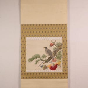 May include: A traditional Japanese hanging scroll featuring a detailed painting of a bird perched on a branch with red and yellow flowers. The scroll has a cream-colored background and a decorative border with a repeating pattern.