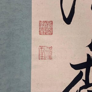May include: An abstract artwork featuring a light blue textured background on the left and a cream-colored background on the right. The cream background has black calligraphy and two red stamps. The calligraphy is in a bold, flowing style.