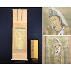 Peut inclure: Peinture sur rouleau japonaise traditionnelle représentant une figure sereine en robe fluide, tenant une fleur de lotus. L'œuvre est principalement jaune et or, avec des détails complexes et un effet de halo. Le rouleau est présenté avec un rouleau en bois et du matériel de suspension.