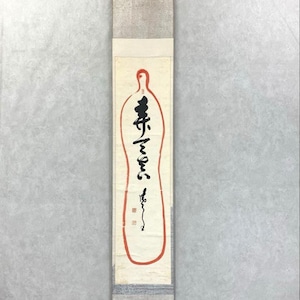 May include: A vertical Japanese scroll with calligraphy in black ink and a red outline. The scroll features a cream-colored background with a red outline in the shape of a bottle. The top and bottom sections have a silver-gray textured design.