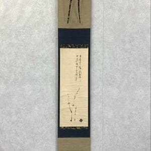 May include: A vertical Japanese scroll painting with a beige and navy blue design. The top section is beige with a dark pattern, and the middle section is navy blue. The scroll features calligraphy and a minimalist branch illustration.