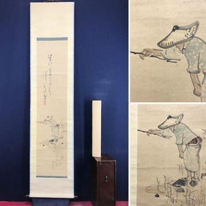 May include: A vertical hanging scroll featuring a light beige background with a hand-painted ink illustration of a figure wearing a wide-brimmed hat and light-coloured clothing, standing in a field. The scroll includes vertical Japanese calligraphy text.