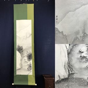 Peut inclure: Peinture sur rouleau verticale représentant un paysage en noir et blanc. Le tableau montre des montagnes, des arbres et un chemin. Le rouleau a une bordure verte et vert olive et des baguettes en bois en haut et en bas.