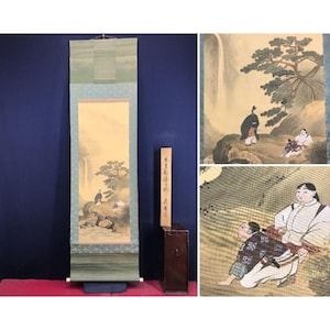 May include: A vertical hanging scroll featuring a painting of a waterfall, a pine tree, and figures in traditional attire. The scroll is presented with a wooden storage box marked with Japanese calligraphy, alongside detailed close-up views.