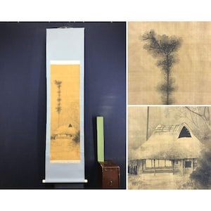 May include: A vintage Japanese scroll painting depicting a landscape with a thatched-roof house and trees. The artwork is in shades of brown and yellow, with a light blue border and wooden dowels at the bottom.