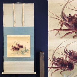 May include: A Japanese scroll painting depicting two lobsters in shades of red and brown, with long antennae and delicate legs. The artwork is set against a light background with green foliage, and is framed by blue and cream-coloured paper.