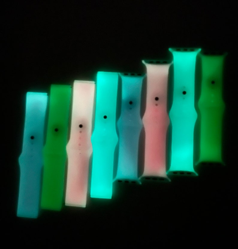 May include: Eight glow-in-the-dark watch bands in different colors, including blue, green, pink, and turquoise. The bands are made of silicone and are designed for Apple Watches.