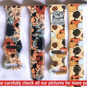 May include: Four different patterned watch bands. The bands are all black with different colourful designs. The designs include floral patterns, pumpkins, and the text "'Tis the season for pumpkin everything".