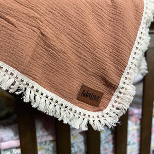 May include: A brown muslin baby blanket with white fringe trim and a personalized name tag that says "Adaline".