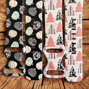 May include: Four different patterned watch bands. The bands are black with white pumpkins, white with green pumpkins, white with pink and black trees, and white with pink and black stripes and cow print.