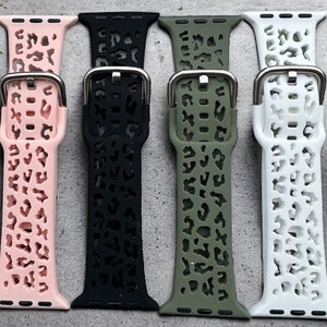 Puede incluir: Cuatro correas para Apple Watch en rosa, negro, verde y blanco con un diseño de estampado de leopardo.