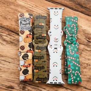 May include: Four different patterned watch bands. The bands are green with plaid trucks, white with snowmen, green with candy canes and holly, and yellow with pumpkins and the text "Tis the season for pumpkin everything".