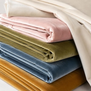 A stack of colorful velvet fabric in various shades of pink, green, blue, and orange.