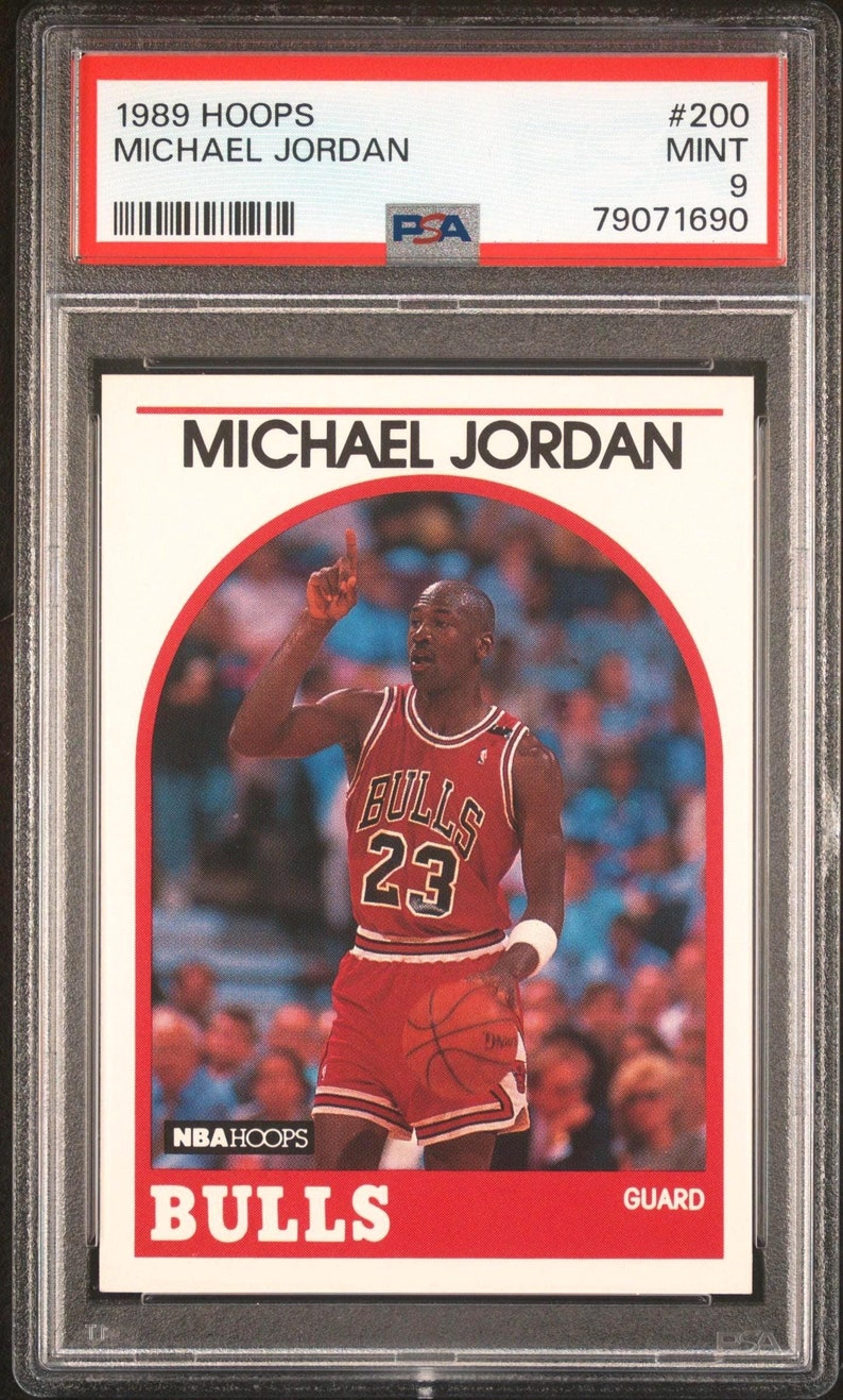 May include: A 1989 NBA Hoops trading card featuring Michael Jordan in his Chicago Bulls uniform. The card is numbered #200 and is graded a 9 by PSA.