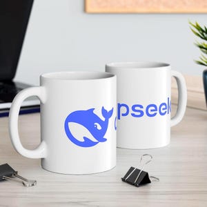 Op de afbeelding: Twee witte keramische mokken met blauwe ontwerpen. De ene mok heeft een blauw walvislogo en de andere mok zegt "Opseek".
