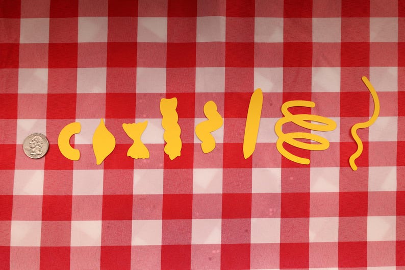 May include: A collection of yellow pasta shapes, including elbow macaroni, shells, bow ties, and spirals, arranged on a red and white checkered tablecloth. A U.S. quarter is included for size comparison.