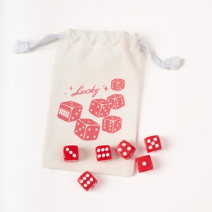 May include: A white canvas bag with a red print of dice and the word "Lucky".  Seven red dice with white dots are scattered around the bag.