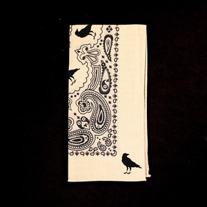 May include: A cream-colored bandana with a black paisley pattern and black crow silhouettes.