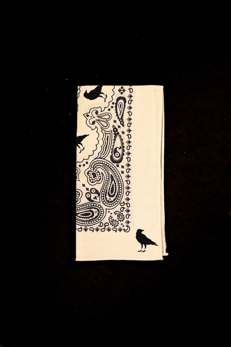 May include: A cream-colored bandana with a black paisley pattern and black crow silhouettes.