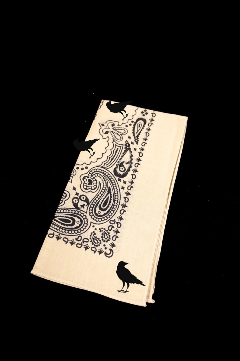May include: A beige bandana with a black paisley pattern and black crow silhouettes.