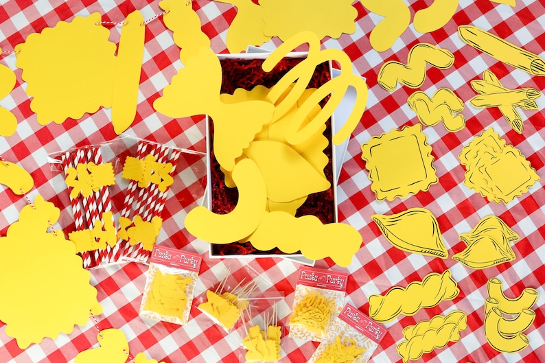 May include: A collection of yellow pasta-themed decorations and party supplies on a red and white checkered tablecloth. Includes various pasta shapes, paper straws, and small bags labeled "Pasta Party."