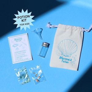 May include: A mermaid potion kit for kids, featuring a white drawstring bag with a seashell design and the words "Mermaid Potion." The kit includes a small glass bottle, a funnel, a checklist, and small bags of glitter and shells, all on a blue surface.